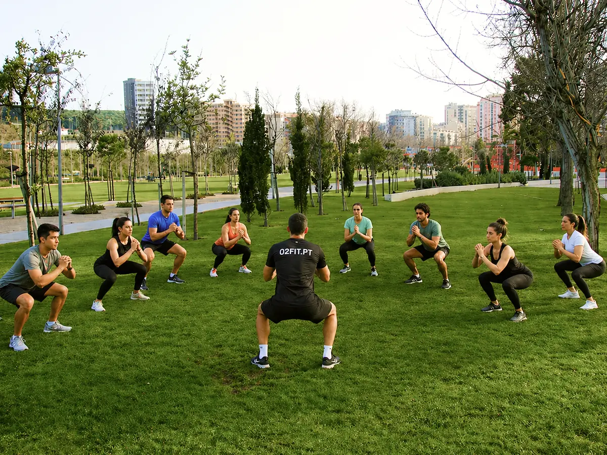 Grupo da O2Fit a fazer agachamentos em roda com o instrutor no Parque Urbano de Miraflores
